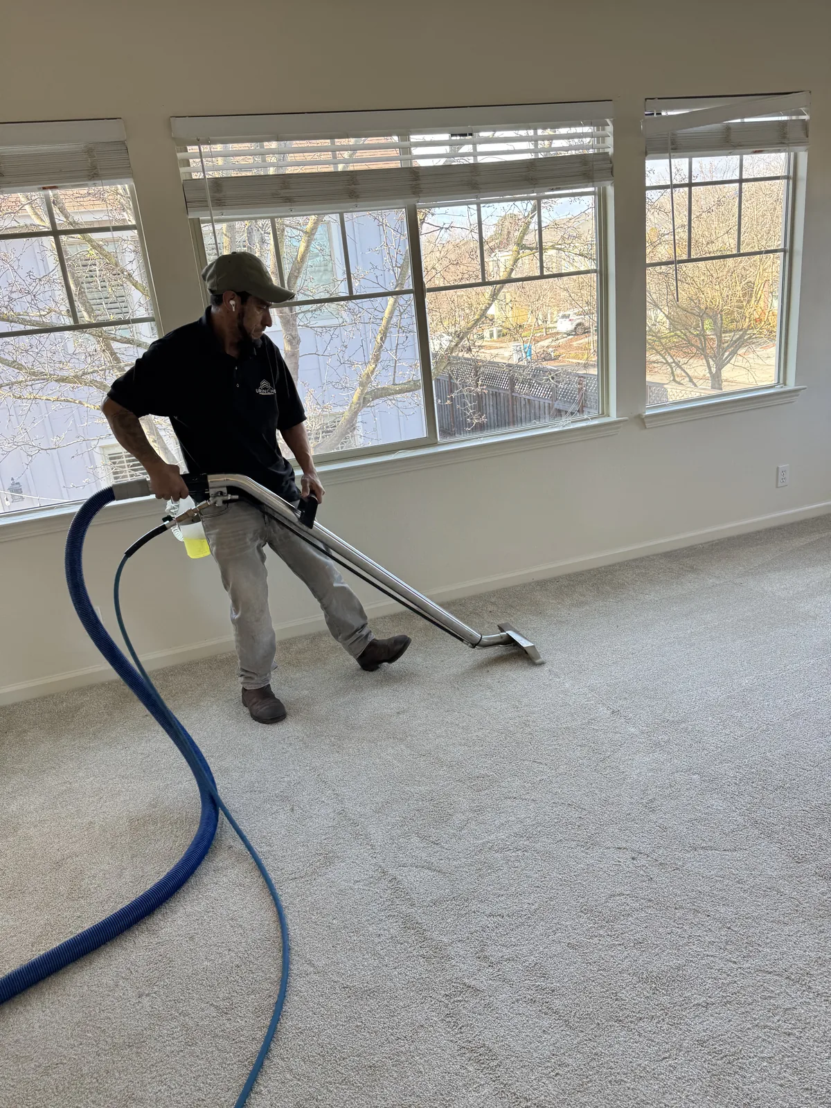 Technician steam cleaning carpet in an empty room