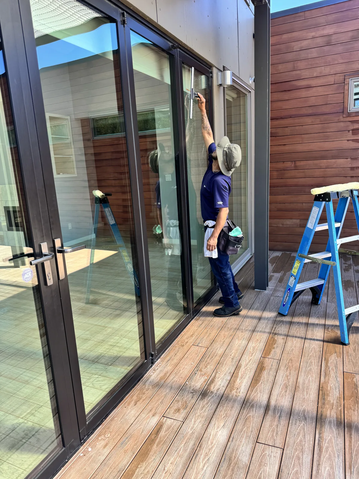 Technician cleaning tall glass doors at an entry