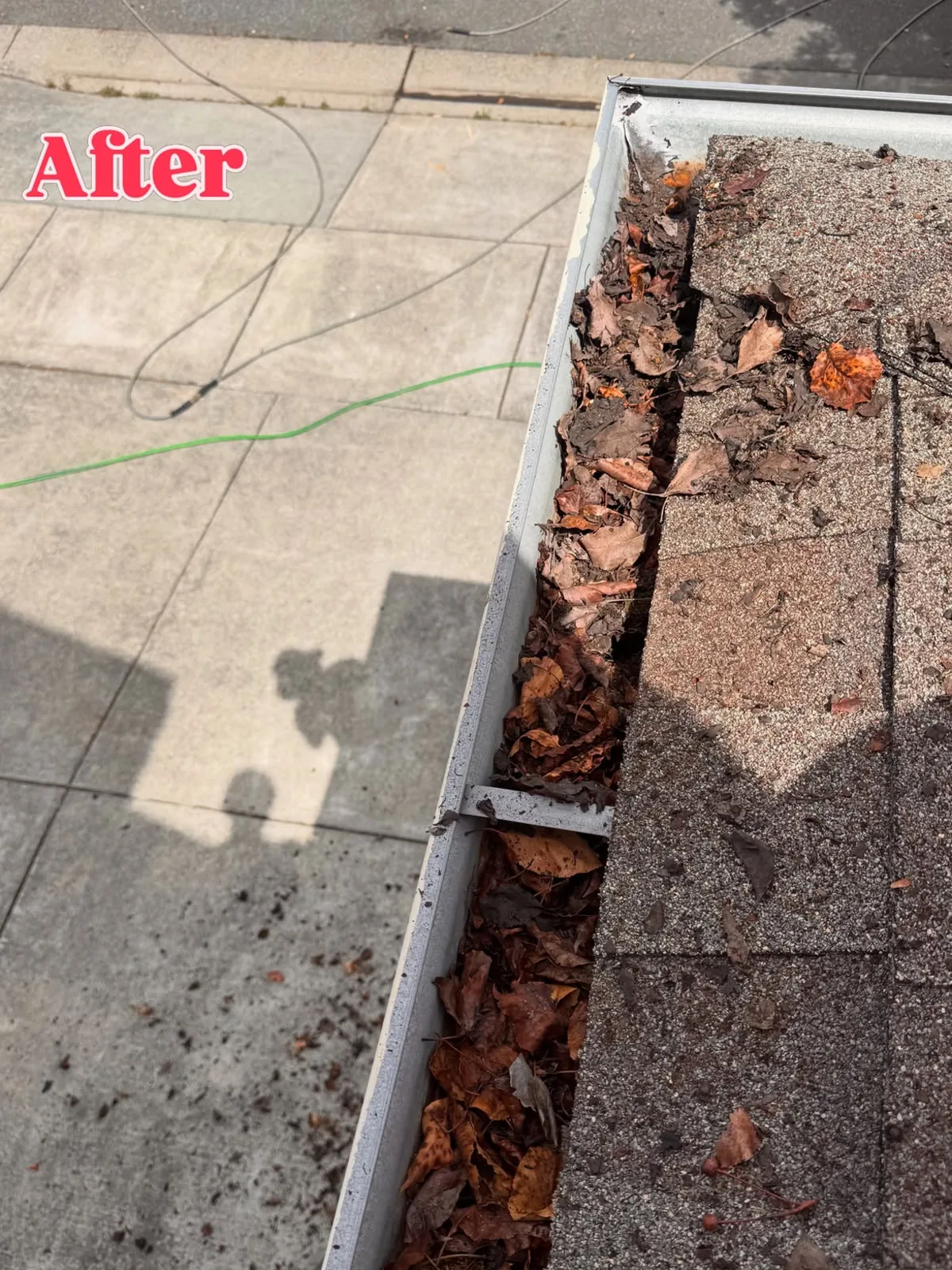 Leaf and debris buildup cleared from a roof gutter