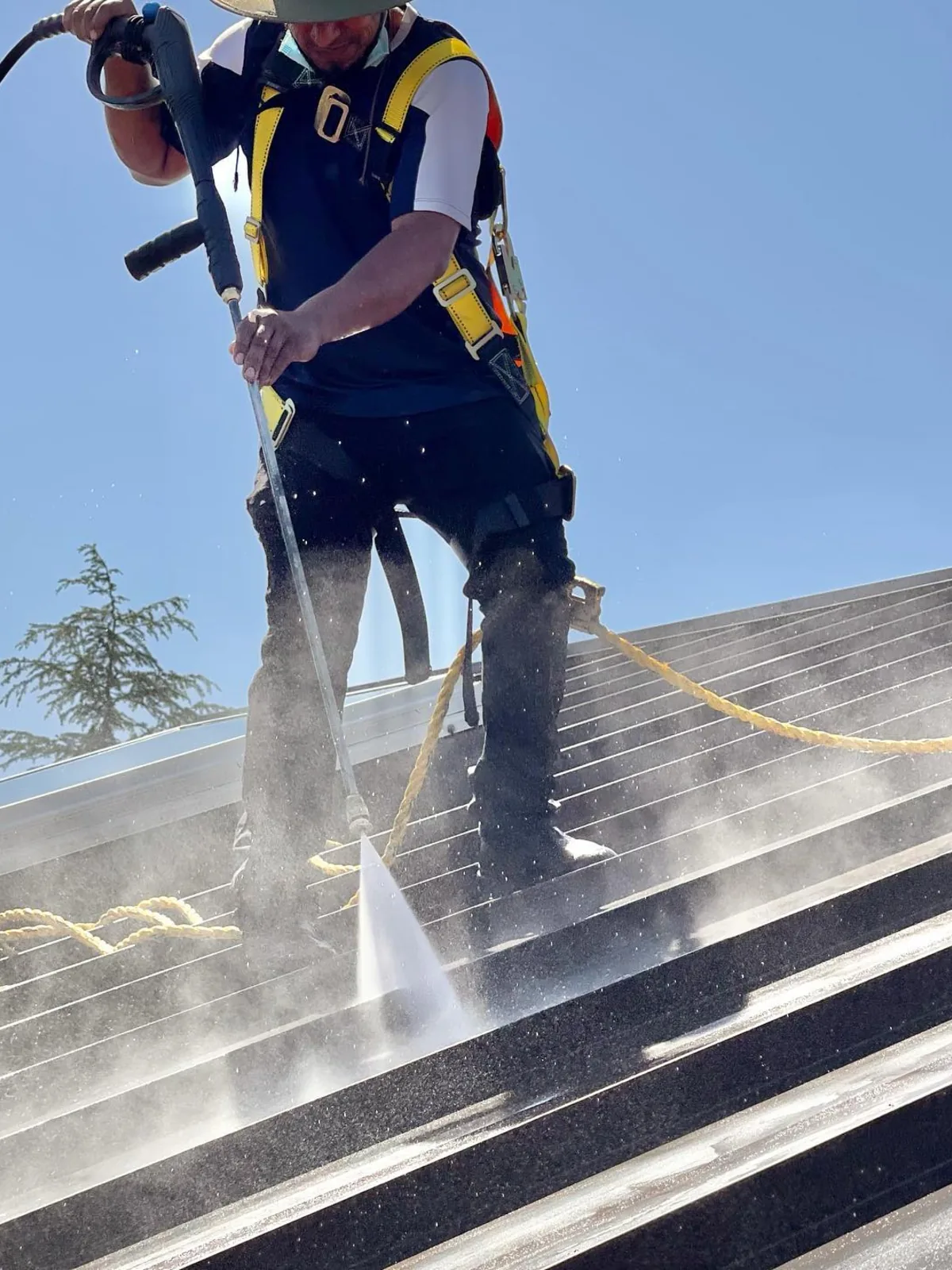 Hot pressure washing a metal roof from a harness