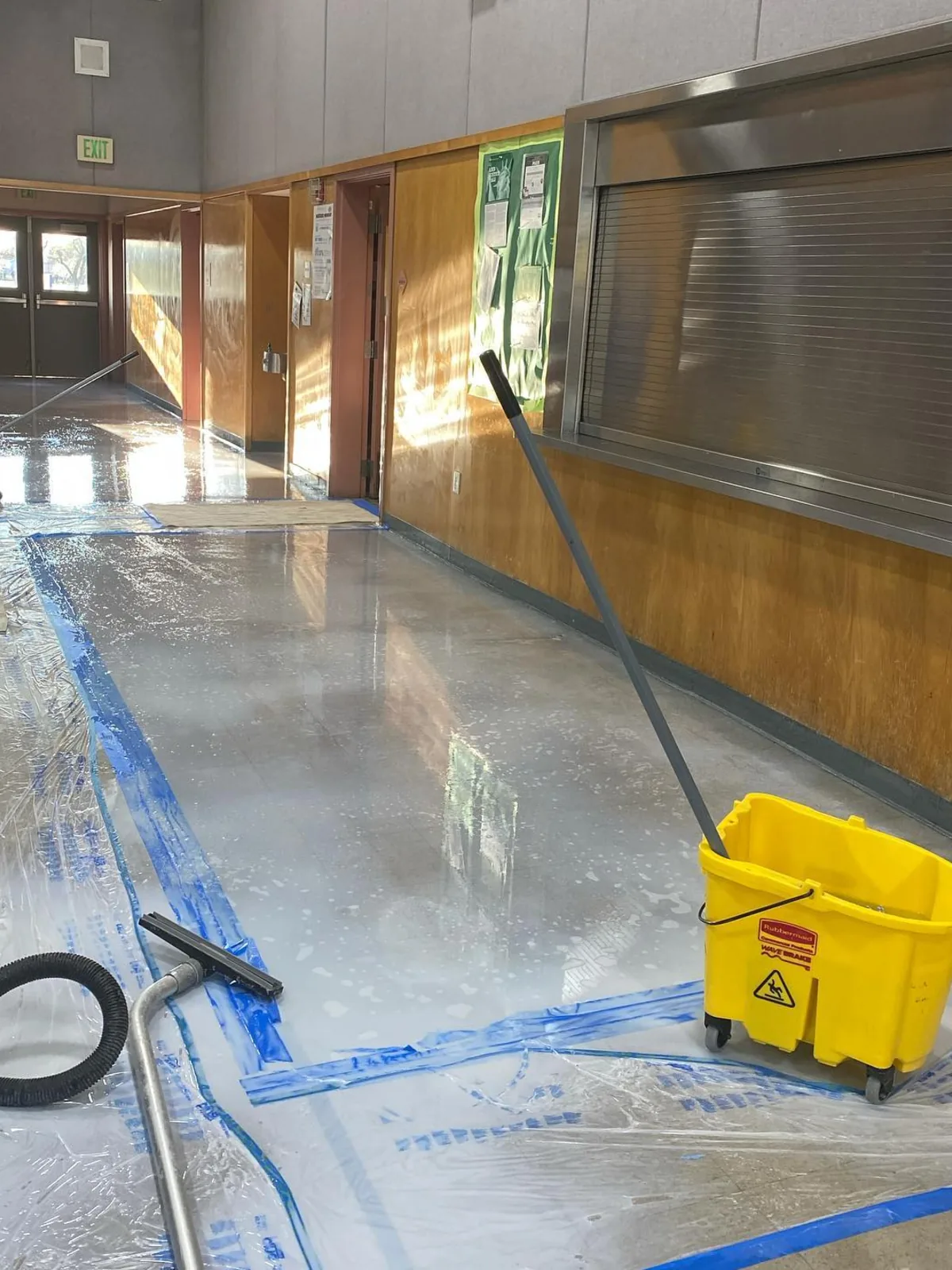 Squeegee cleaning storefront glass with floor protection