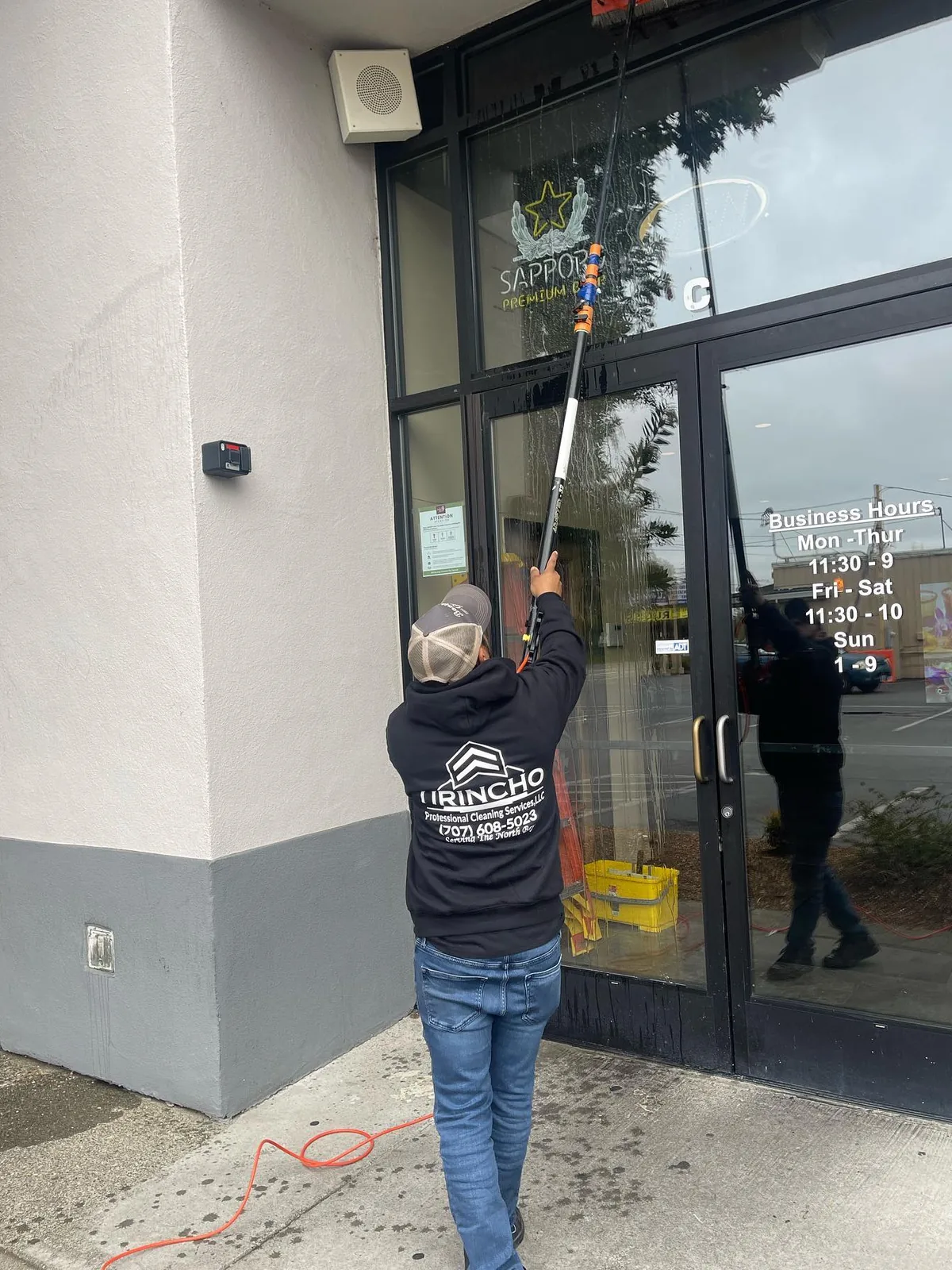 Water-fed pole cleaning a storefront glass entry